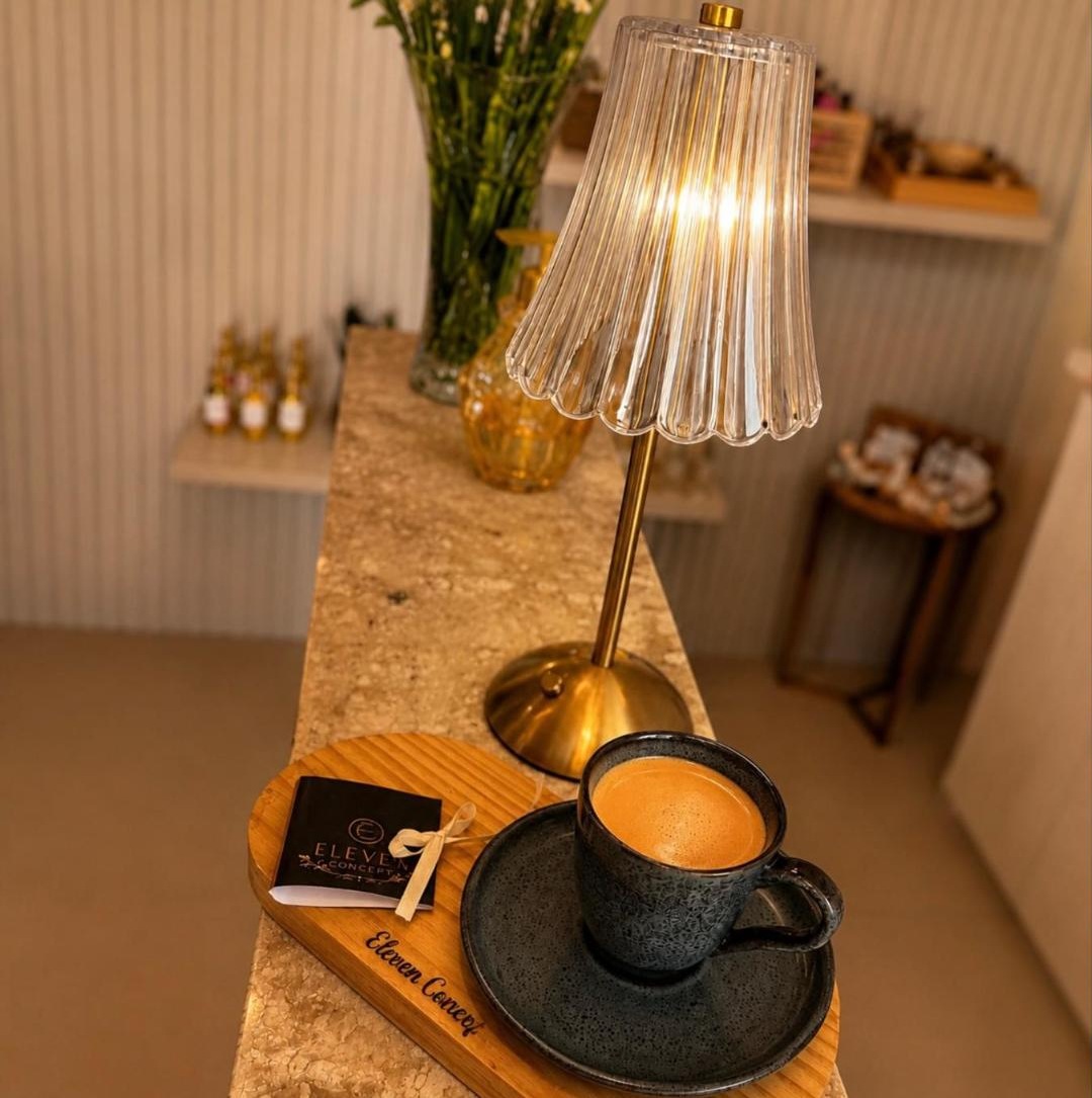 Balcão da recepção do Eleven Concept com café servido, luminária de latão e o cartão do salão